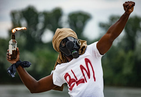 Person in gas mask with Molotov cocktail, BLM shirt.
