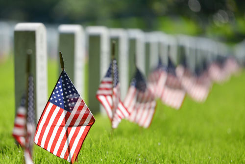 American flags beside gravestones in a cemetery.