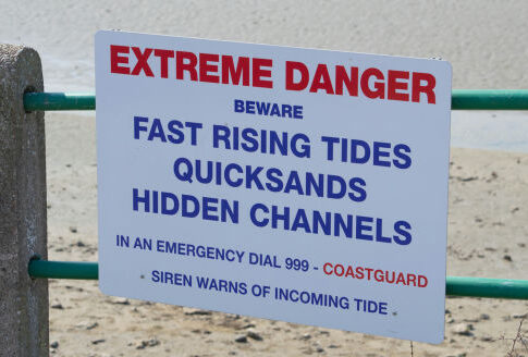 Sign warning of tides, quicksand, hidden channels.