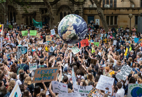 Large climate change protest with many signs and globe balloon.